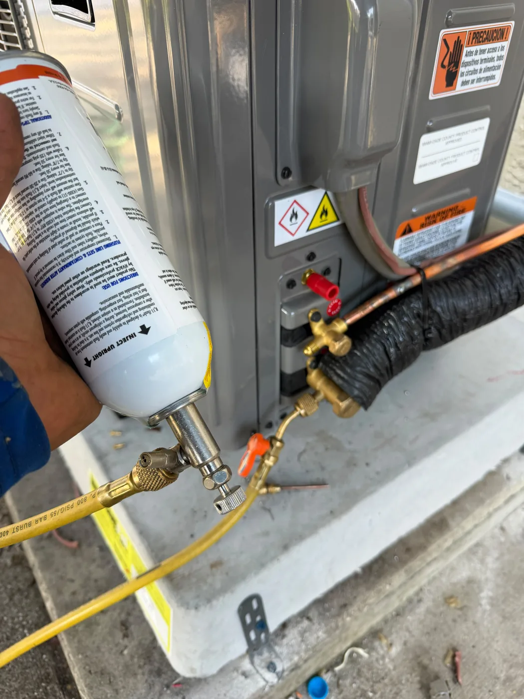 Technician flushing the refrigerant line set at a Ruud outdoor unit